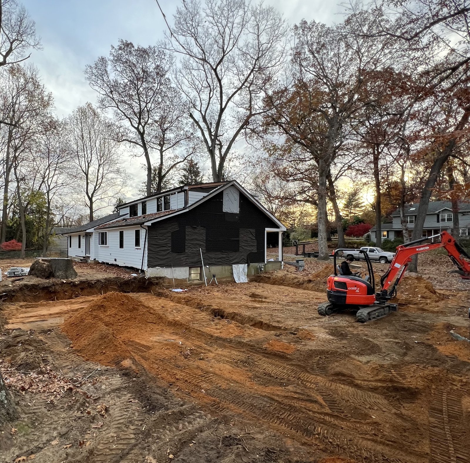 Site excavation at sunset with branded equipment